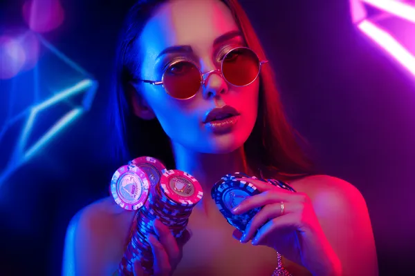 Một người phụ nữ quyến rũ cầm chip casino trong không gian ánh đèn rực rỡ, đại diện cho bầu không khí casino trực tuyến của F8BEF.